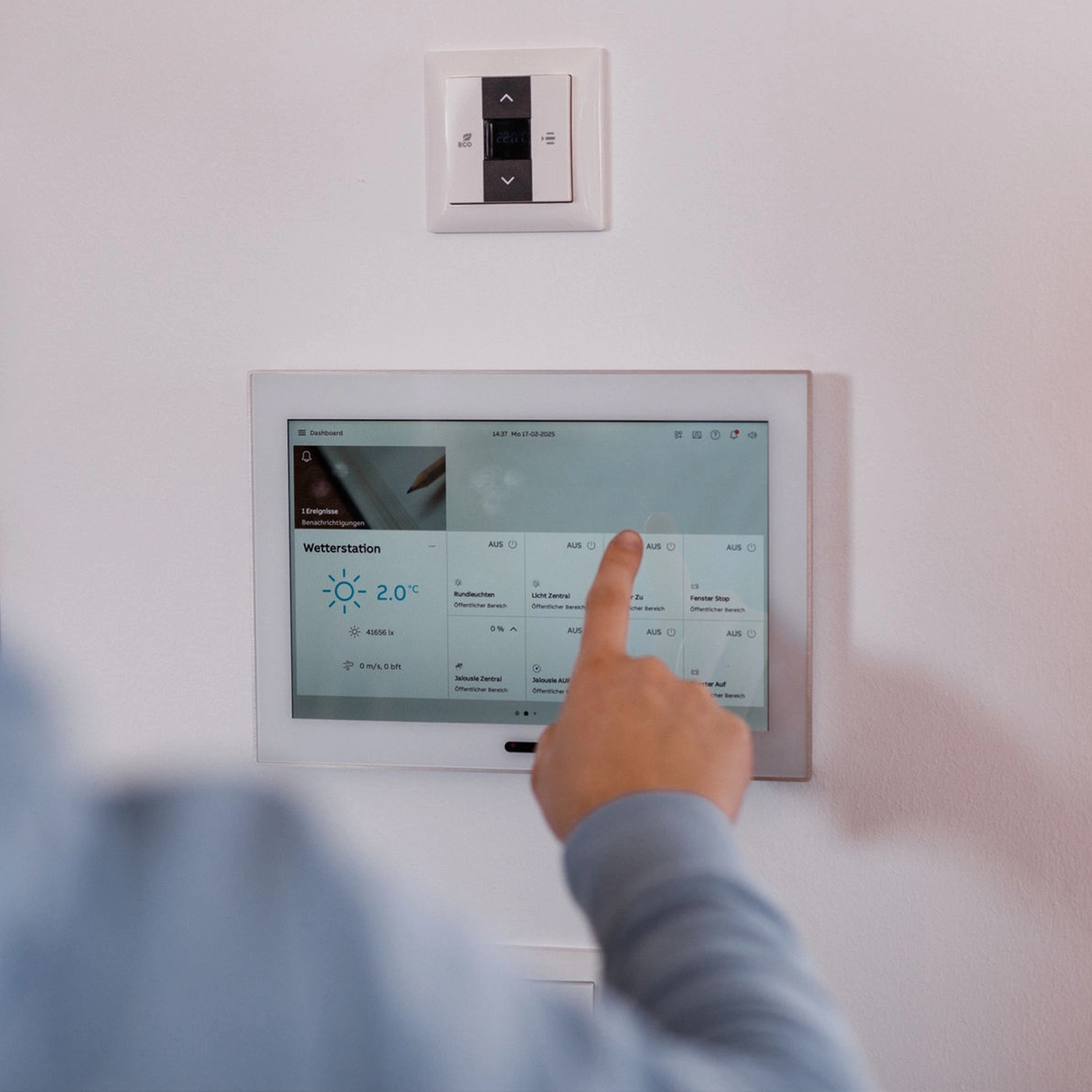 Person verwendet ein Smart-Home-Panel an der Wand.