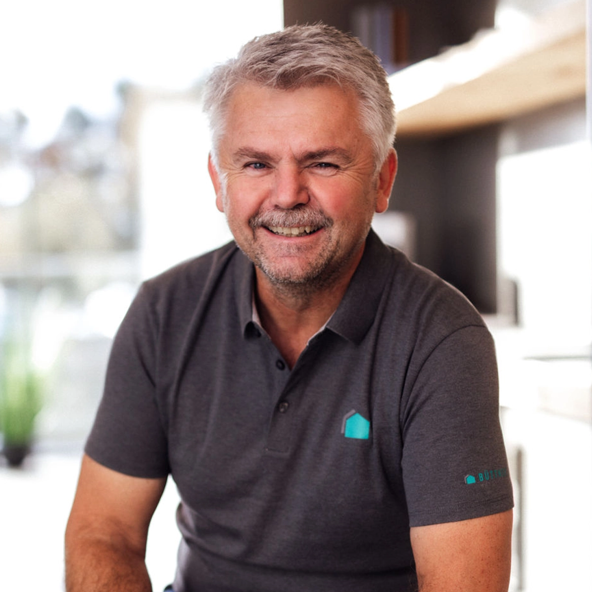 Eddi lächelnd in grauem Polo-Shirt.