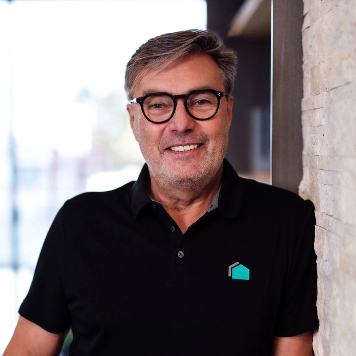 Manfred lächelt in die Kamera vor einer Steinwand.