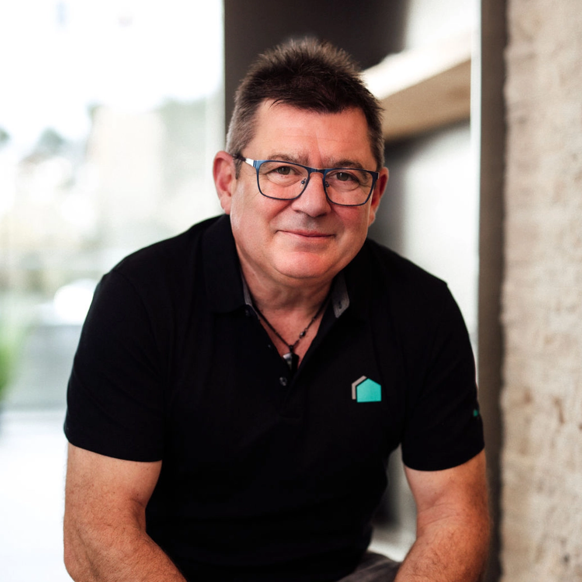 Volker sitzt lächelnd vor unscharfem Hintergrund.