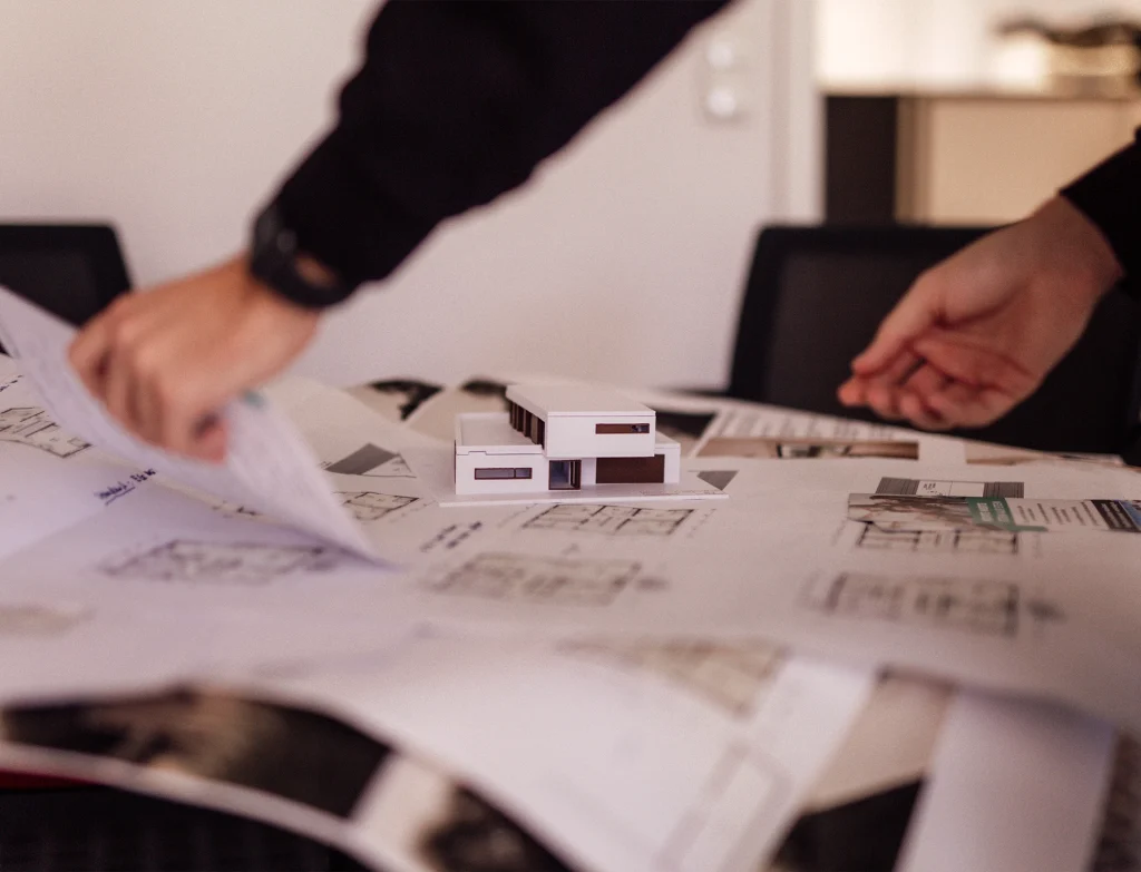 Architekten arbeiten mit Entwürfen und einem Modell.