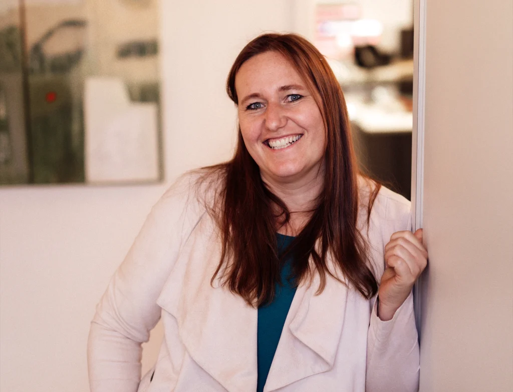 Andrea lächelnd an einer Wand.