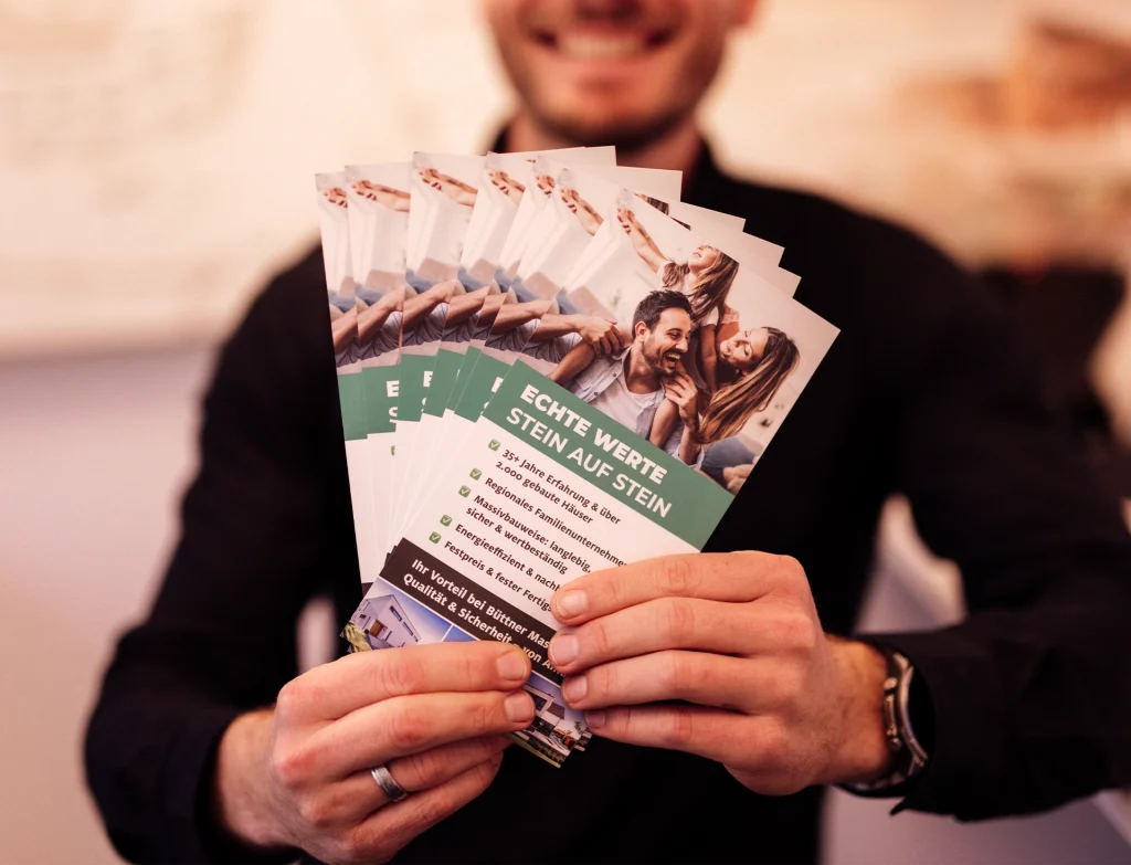 Dominik Büttner hält Werbeflyer über Echte Werte - Stein auf Stein