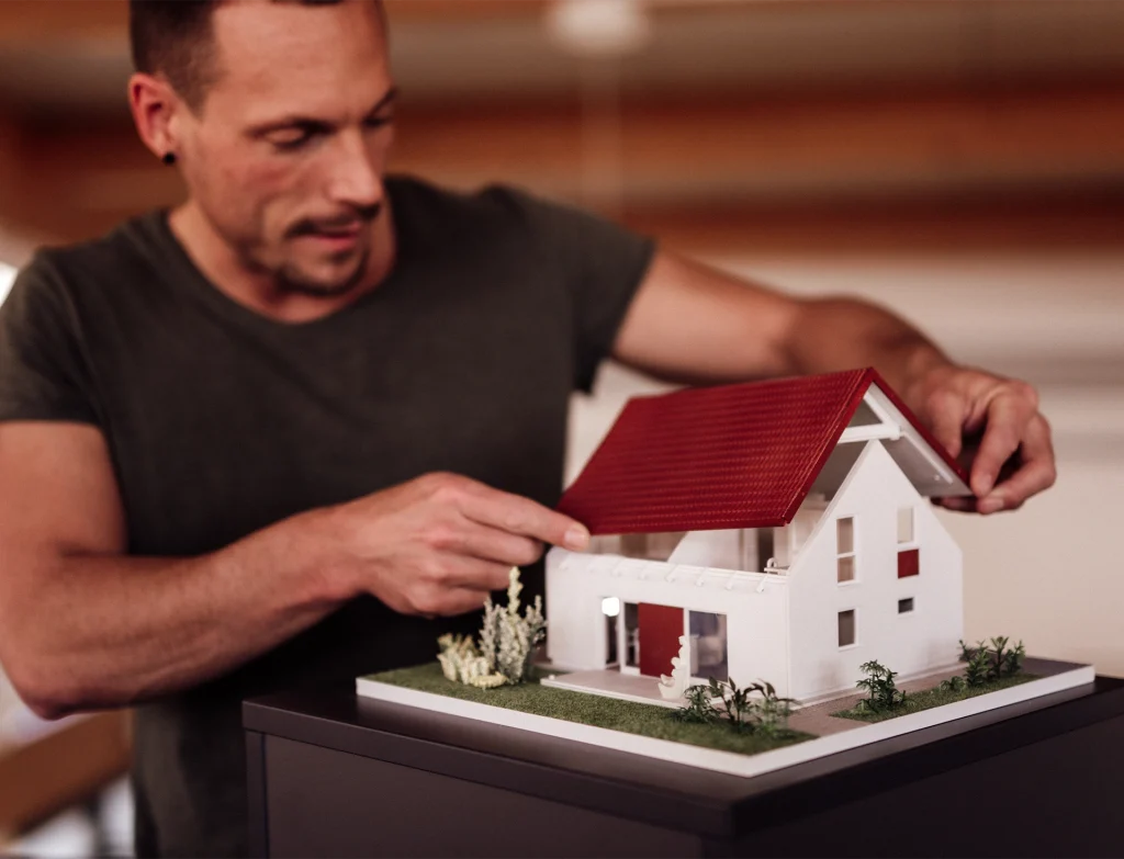 Philiüü prüft ein Hausmodell und nimmt das Dach ab.