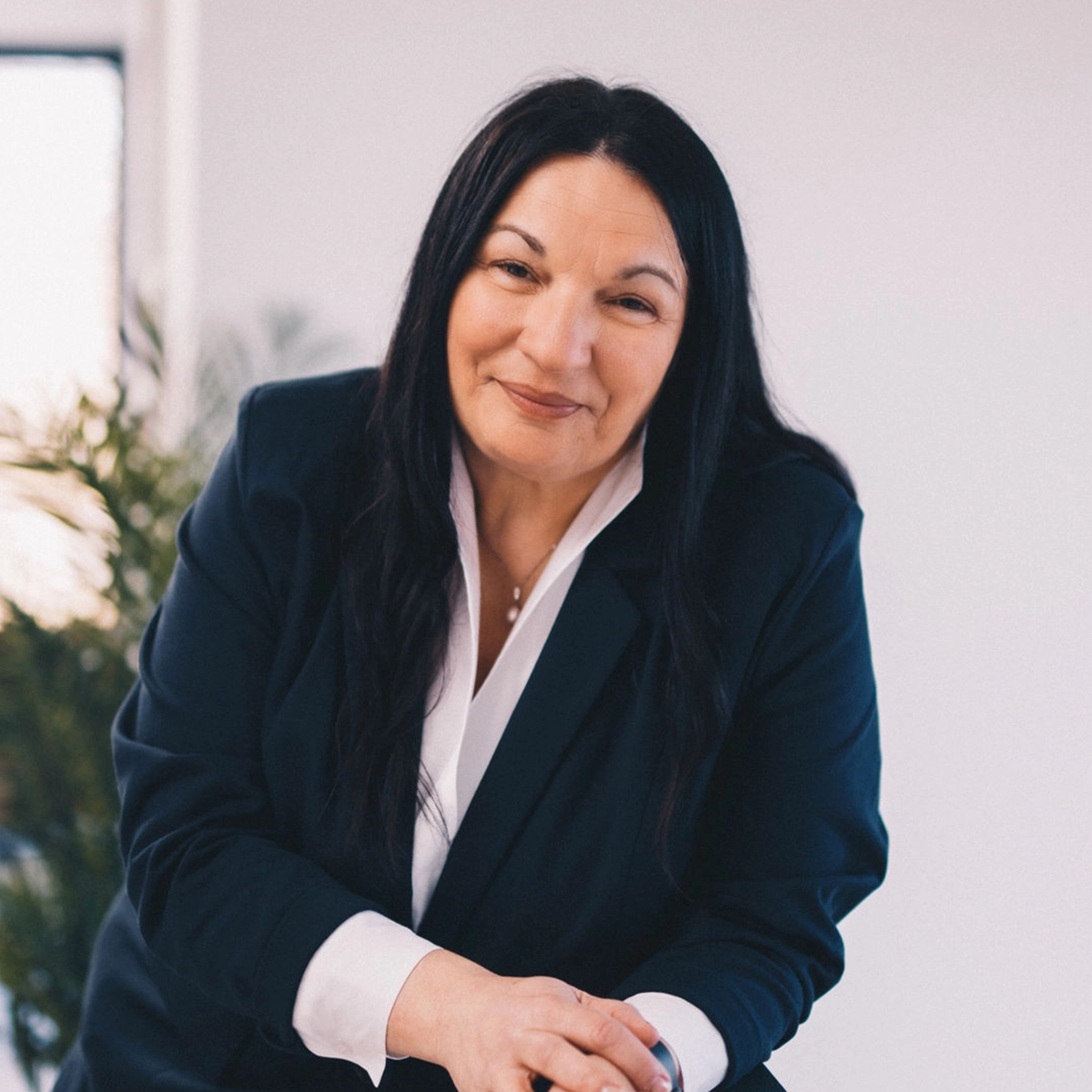 Manuela in einem Anzug lächelt in die Kamera.