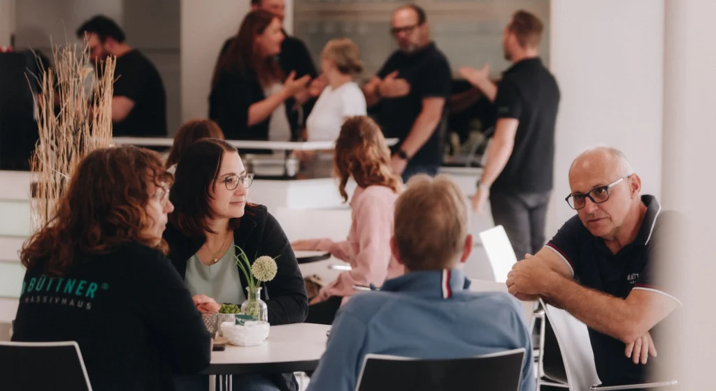 Mitarbeitende von Büttner Massivhaus im Gespräch bei einem gemeinsamen Teamtreffen.