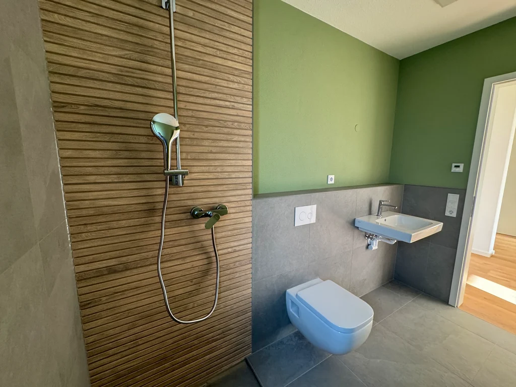 Modernes Duschbad mit bodengleicher Dusche, stilvoller Holzoptik und harmonischer Farbgestaltung.