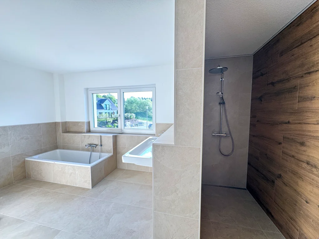 Stilvoll gestaltetes Familienbad mit offener Dusche, hochwertigen Materialien und viel Tageslicht.