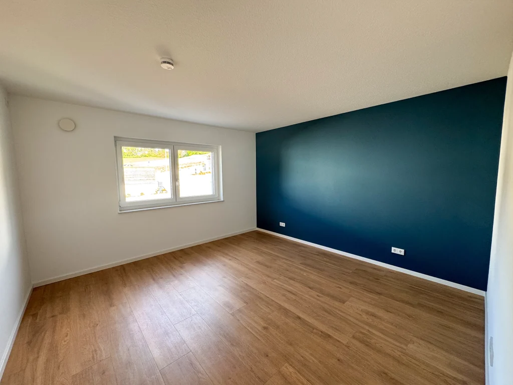 Modernes Zimmer mit stilvoller Akzentwand in Dunkelblau und angenehmer Wohnatmosphäre.
