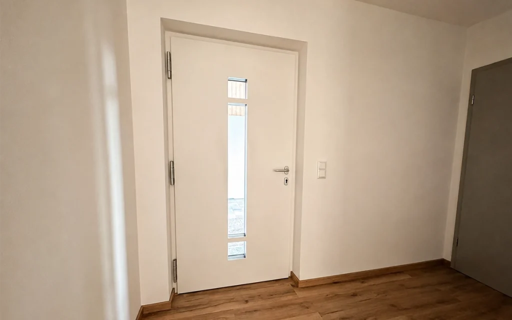 Heller Eingangsbereich mit moderner Haustür und hochwertigem Holzoptikboden.