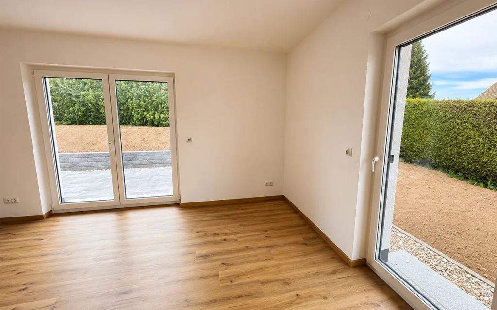 Heller Wohn- und Essbereich mit großen Fensterflächen und direktem Zugang zur Terrasse.