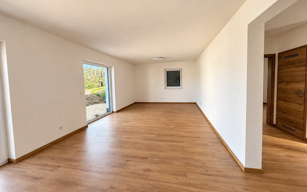 Großzügiges helles Wohnzimmer mit Holzfußboden und großen Fenstern