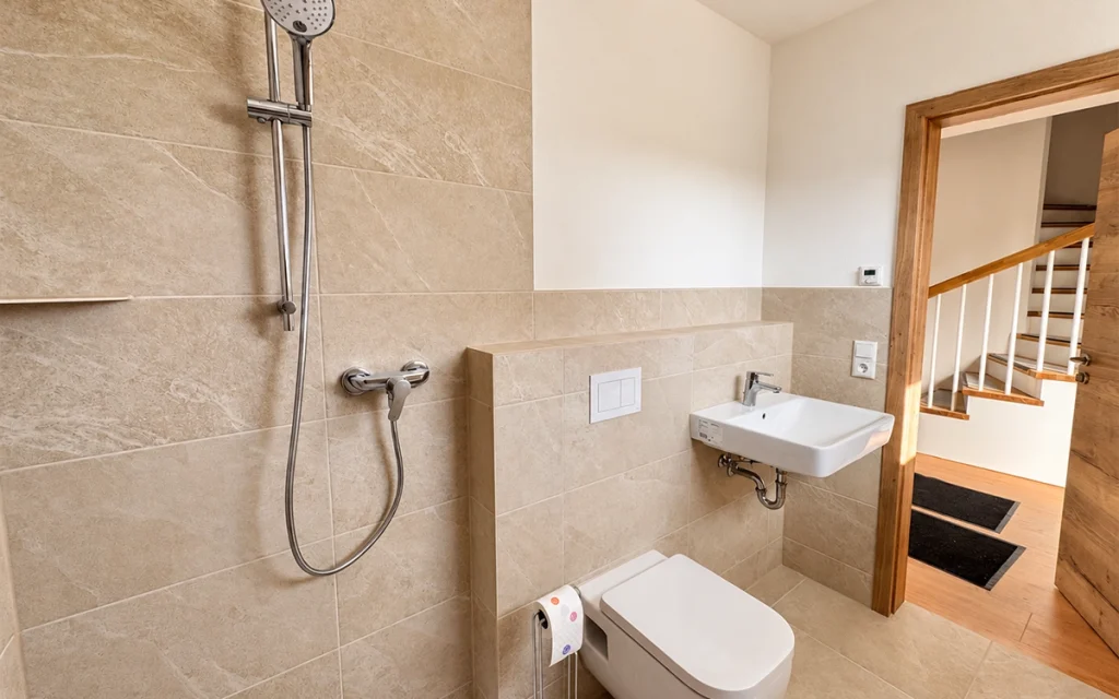 Modernes Gäste-WC mit bodengleicher Dusche und hellen Fliesen