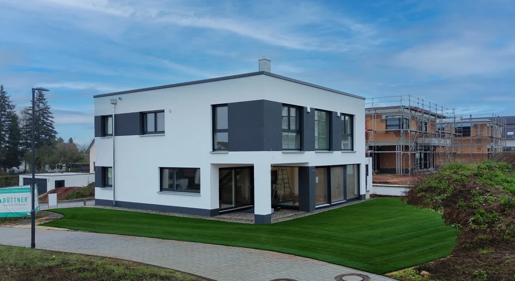 Modernes, kubisches Einfamilienhaus mit Flachdach, klaren Linien und kontrastreicher Fassadengestaltung in Weiß und Anthrazit.