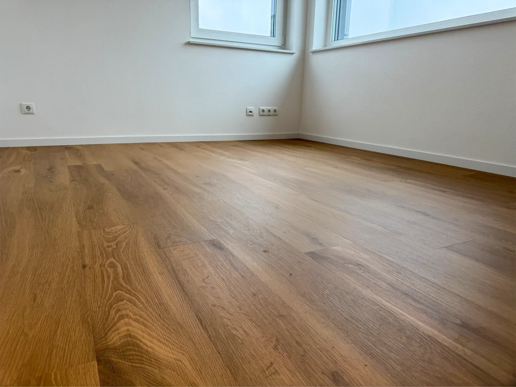 Raumdetail mit hochwertigem Holzfußboden und bodentiefen Fenstern.