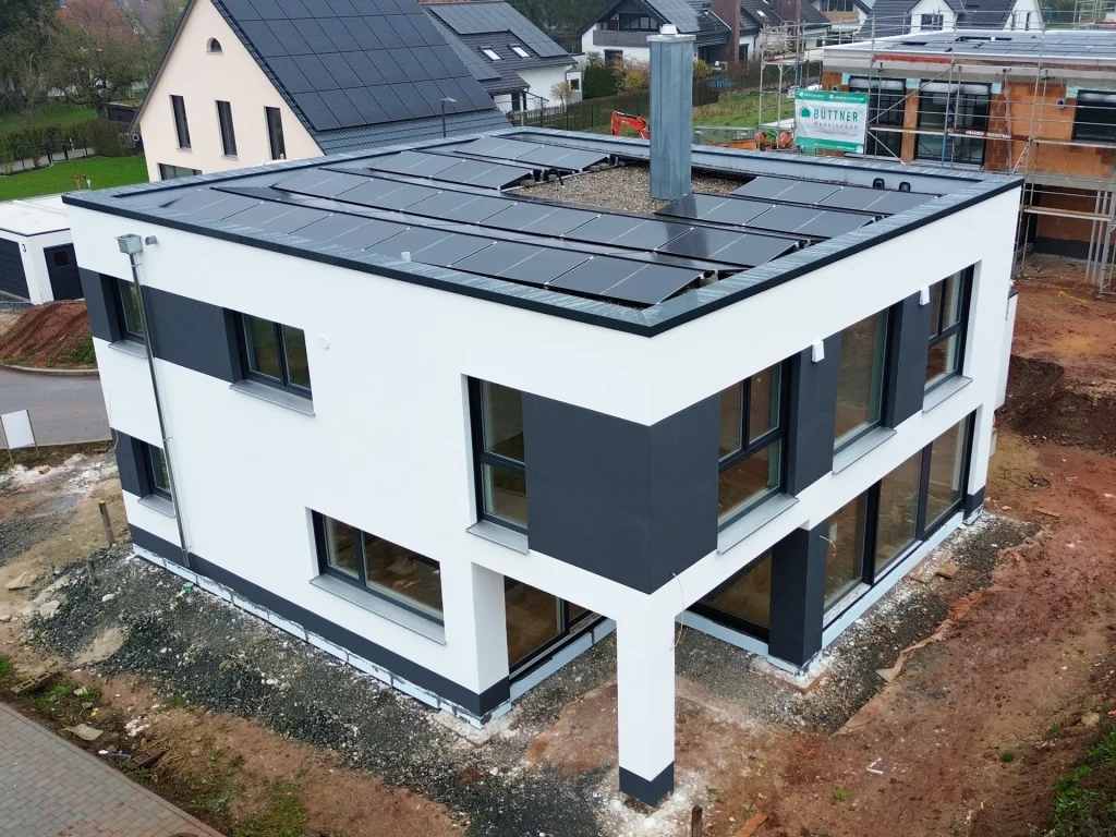 Kubisches Einfamilienhaus mit Flachdach und Photovoltaikanlage in moderner Weiß-Anthrazit-Optik.