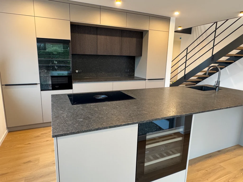 Offener Küchenbereich mit Kochinsel, Induktionsfeld und direktem Blick zur Treppe.