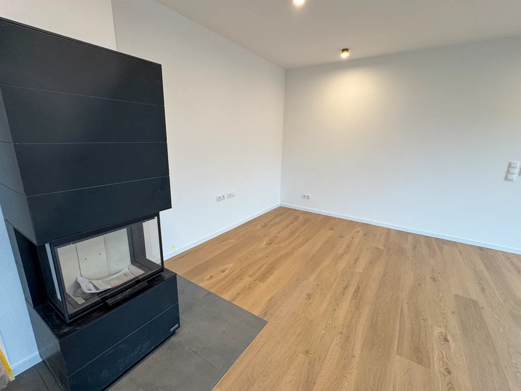 Heller Wohnraum mit moderner Kaminanlage und warmem Holzfußboden.