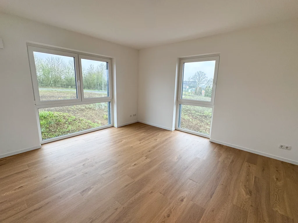 Heller Raum mit großen Fenstern und Blick ins Grüne, ideal als Wohn- oder Schlafzimmer.